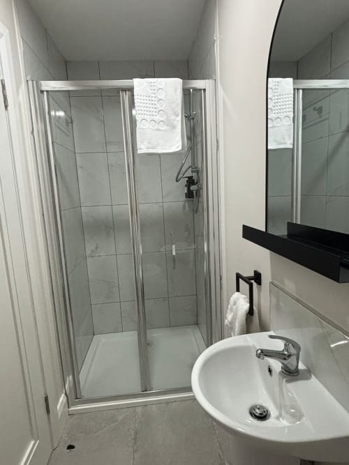 Clean private bathroom at Madeline's Accommodation in Wicklow with shower enclosure, round sink, and towel rail