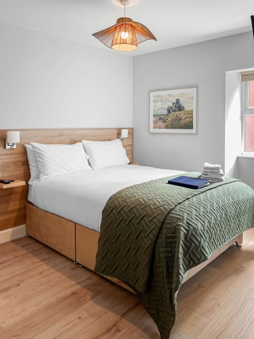 Modern twin bedroom at Madeline's Accommodation in Wicklow with wooden bed, white linens, and green quilted throw