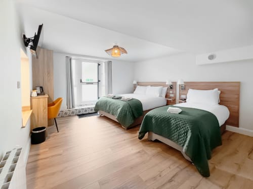 Twin bedroom at Madeline's Accommodation in Wicklow with two beds, green quilts, wooden headboards, and modern amenities