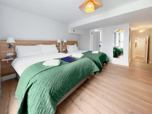 Twin Room at Madeline's Accommodation in Wicklow with dual beds, white linens, green quilts, wooden floors and modern ensuite