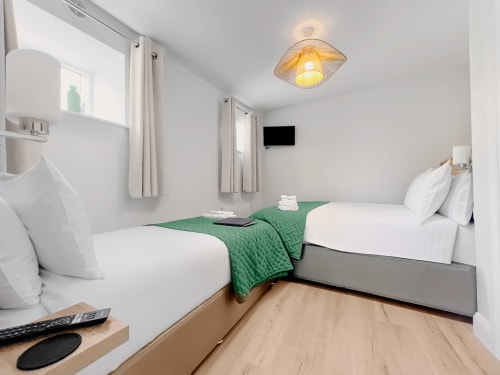 Twin bedroom at Madeline's Accommodation in Wicklow with two beds, green throw, TV, and wooden flooring