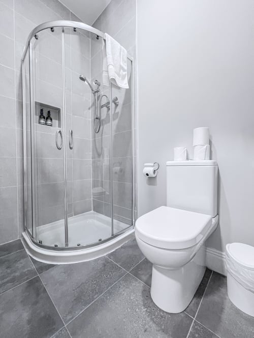 Modern bathroom in Madeline's Accommodation, Wicklow with corner shower enclosure, white toilet, and gray tiled flooring