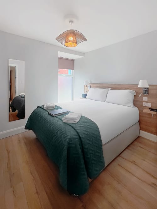 Small Double Room at Madeline's Accommodation in Wicklow with queen bed, wooden headboard, and modern ceiling light