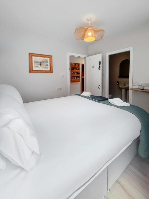 Bright small double bedroom at Madeline's Accommodation in Wicklow with white bed, en-suite bathroom, and modern pendant