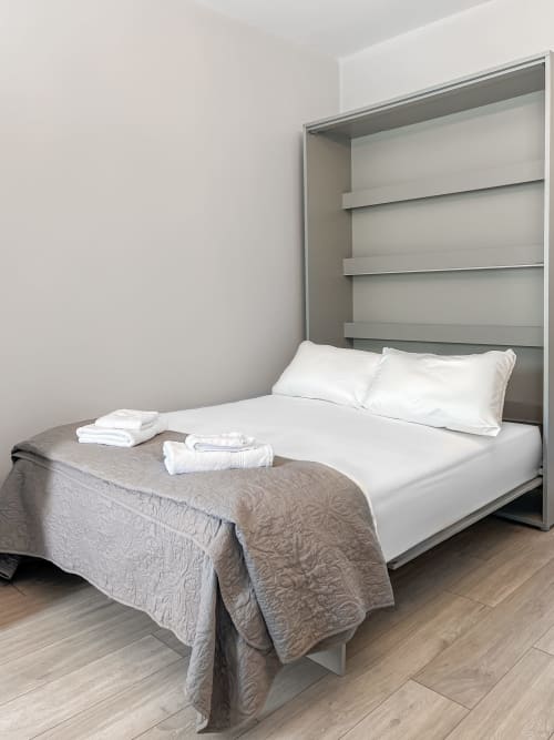 Modern King Studio bedroom at Madeline's Accommodation, Wicklow with built-in shelving, white bedding, and wood flooring