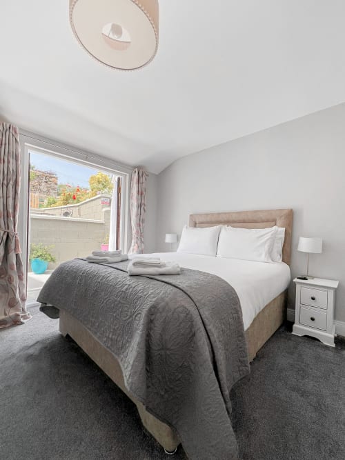 Bright King Studio bedroom at Madeline's Accommodation in Wicklow with white linens, grey bedding, and patio doors