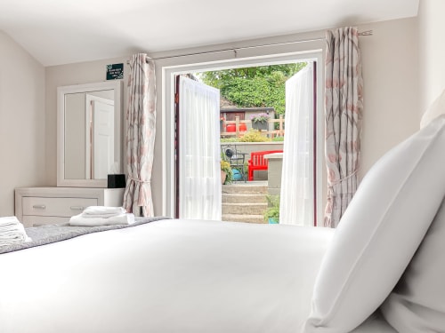 Bright King Studio bedroom at Madeline's Accommodation with garden view through open patio doors, white furnishings and