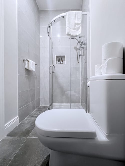 Modern bathroom at Madeline's Accommodation in Wicklow with glass shower enclosure, white toilet, and towel rack