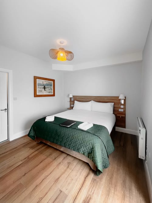Superior double bedroom at Madeline's Accommodation, Wicklow, with wooden bed, green throw, and pendant light fixture