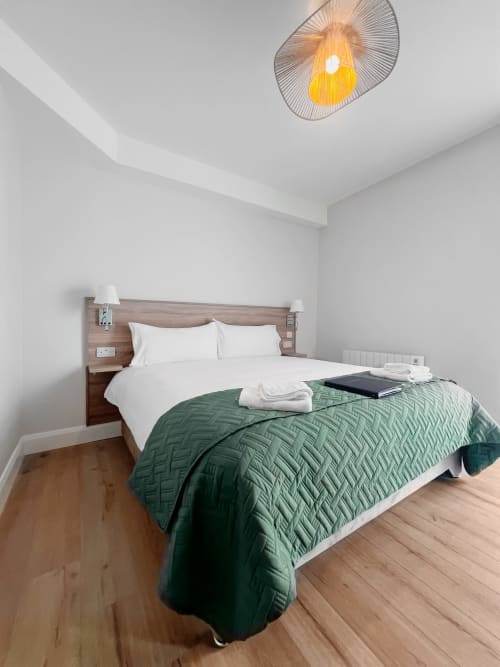 Modern Superior Double bedroom at Madeline's Accommodation in Wicklow with white linens, green quilt, wooden flooring, and