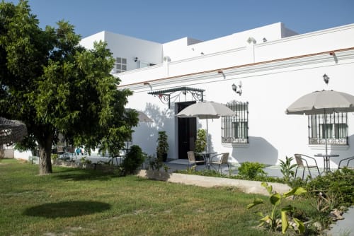 Patio del Hotel Boutique Alcazaba Salobreña con edificio blanco, áreas sombreadas y jardín cuidado en Granada, España