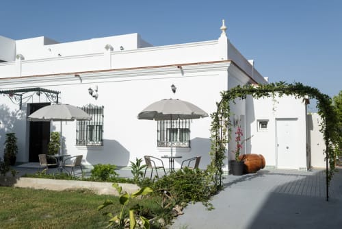 Patio del boutique hotel Alcazaba Salobreña con arquitectura blanca, sombrillas, zona de estar y pérgola cubierta de hiedra