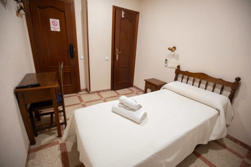 Habitación del hotel San Poul en Consuegra con camas dobles, muebles de madera, escritorio y vistas a la ciudad
