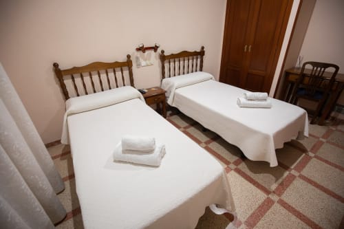 Habitación doble con dos camas individuales en el hotel San Poul de Consuegra, España, con muebles de madera y ropa de cama blanca