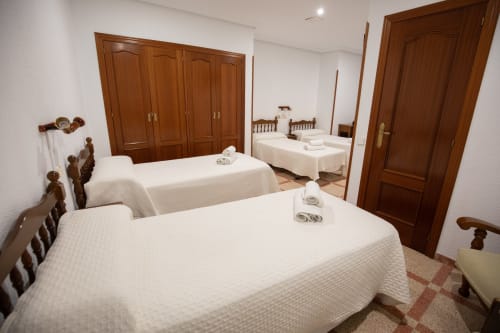 Habitación cuádruple del hotel San Poul en Consuegra con múltiples camas, armarios de madera y decoración tradicional