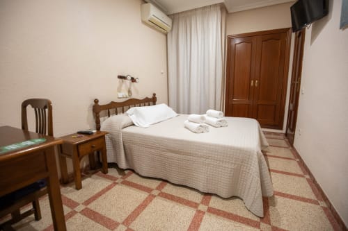 Habitación doble del hotel San Poul en Consuegra con cama de madera, TV y decoración tradicional