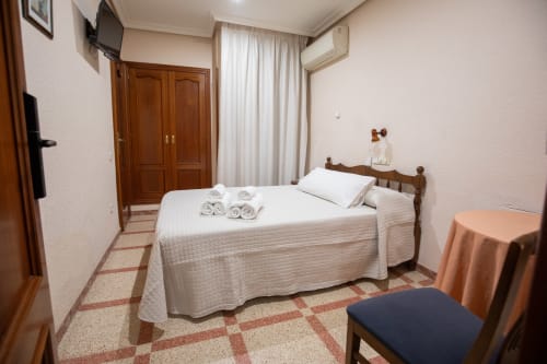 Habitación doble del hotel San Poul en Consuegra con cama, toallas, televisor y comodidades modernas
