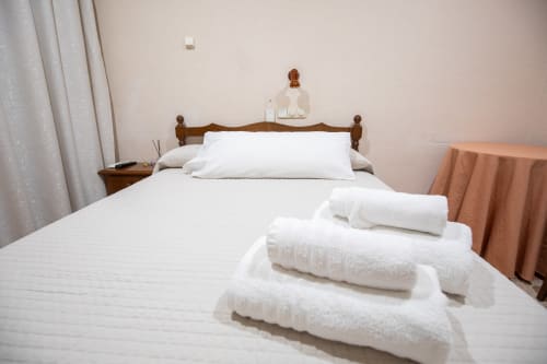 Habitación doble del hotel San Poul en Consuegra con ropa de cama blanca, cabecero de madera y toallas limpias