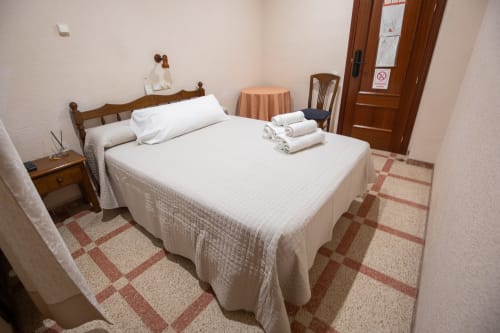 Habitación doble del hotel San Poul en Consuegra con cama de madera, ropa de cama blanca y decoración tradicional
