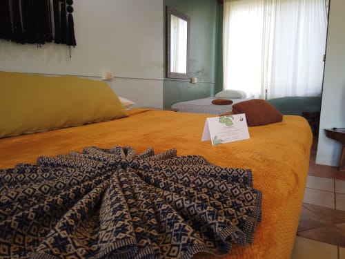 Cama naranja brillante con manta geométrica en habitación tradicional del hostal Cayuco Maya, Bacalar
