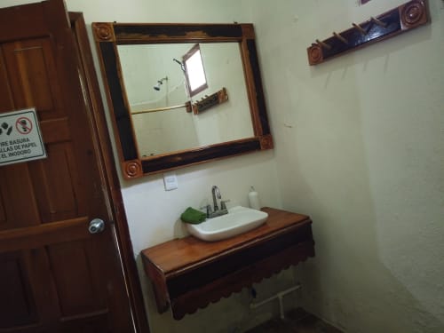 Lavamanos de madera rústica con lavabo blanco en el albergue Cayuco Maya de Bacalar, México