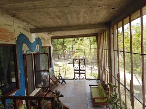Habitación del hostal Cayuco Maya en Bacalar con vistas al jardín, vigas de madera, obra azul y terraza abierta con vista tropical