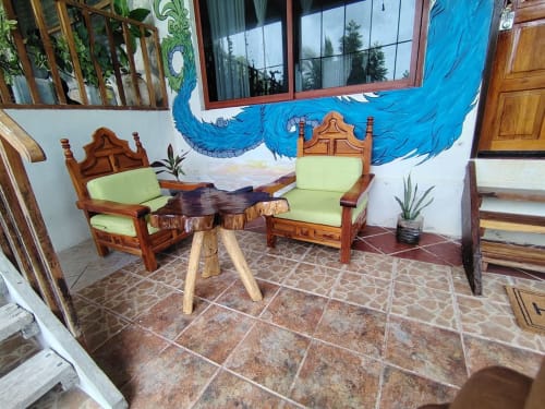 Sillas de descanso de madera con cojines lima y mesa rústica en el hostal Cayuco Maya en Bacalar, México