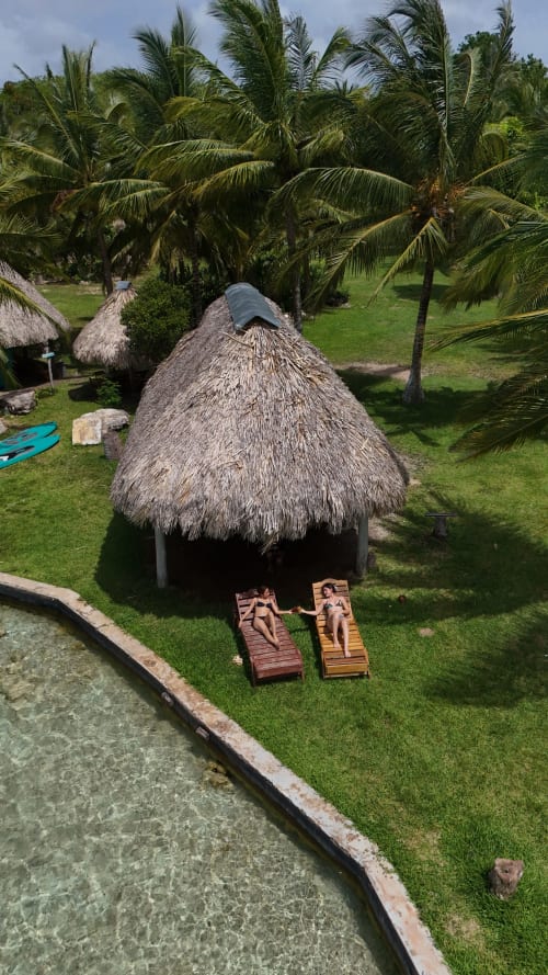 Bungaló con techo de palma en Cayuco Maya hostel, Bacalar, con hamacas y vistas al jardín y palmeras