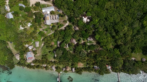 Vista aérea del hostel Cayuco Maya en Bacalar con laguna turquesa, jardines exuberantes y bungalows frente al mar