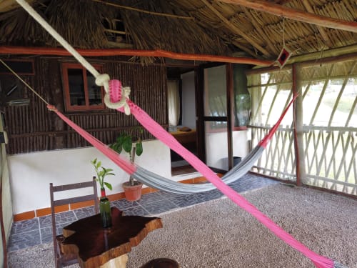 Hamaca rosa en el porche de una cabaña tradicional del hostal Cayuco Maya en Bacalar con vista al lago