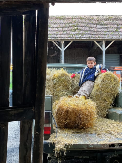 Jeune garçon jouant dans des balles de foin aux gîtes de Cormenin, Saint-Hilaire-sur-Puiseaux, France
