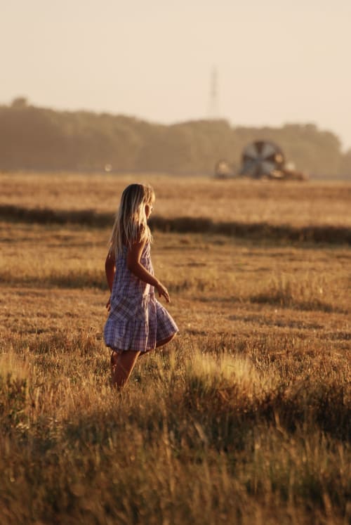Fille en robe à carreaux dans un champ moissonné près des gîtes de Cormenin, Saint-Hilaire-sur-Puiseaux