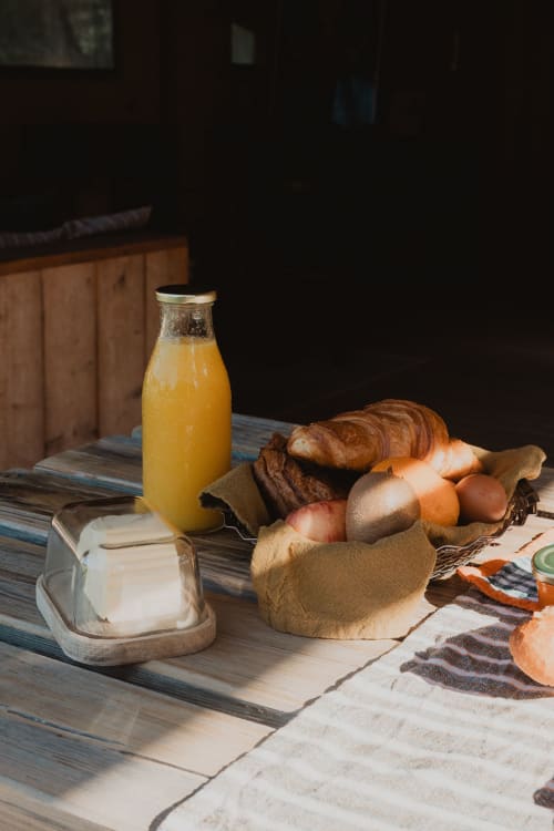 Petit-déjeuner rustique aux gîtes de Cormenin avec pain frais, produits locaux, beurre et jus d'orange sur table en bois