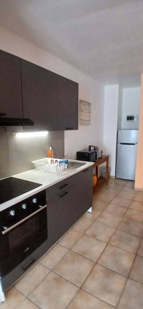 Modern kitchen in Impasse 4 apartment at Les Petits Nids De Nina, Fosses-la-Ville with dark cabinetry and white appliances