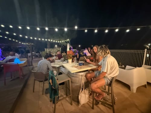 Soirée conviviale à la terrasse de ALMA ROSSA à Lecci avec guirlandes lumineuses et convives dînant en plein air