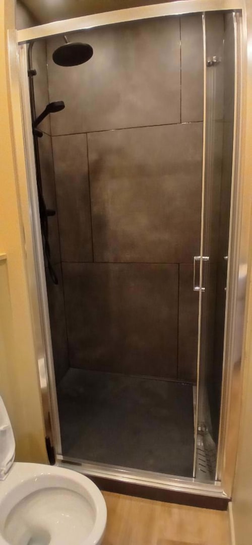 Modern glass shower enclosure with black tile walls and chrome fixtures in Impasse 4 apartment at Les Petits Nids De Nina