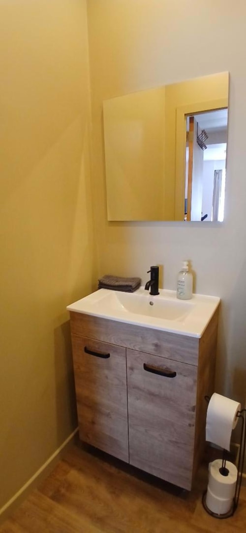 Modern bathroom vanity with wooden cabinets, white sink, and yellow accent walls at Les Petits Nids De Nina, Fosses-la-Ville