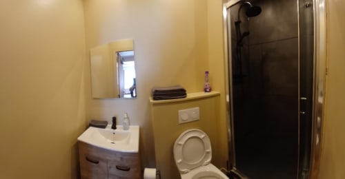 Modern bathroom in Impasse 4 apartment at Les Petits Nids De Nina with yellow walls, sink, toilet, and shower
