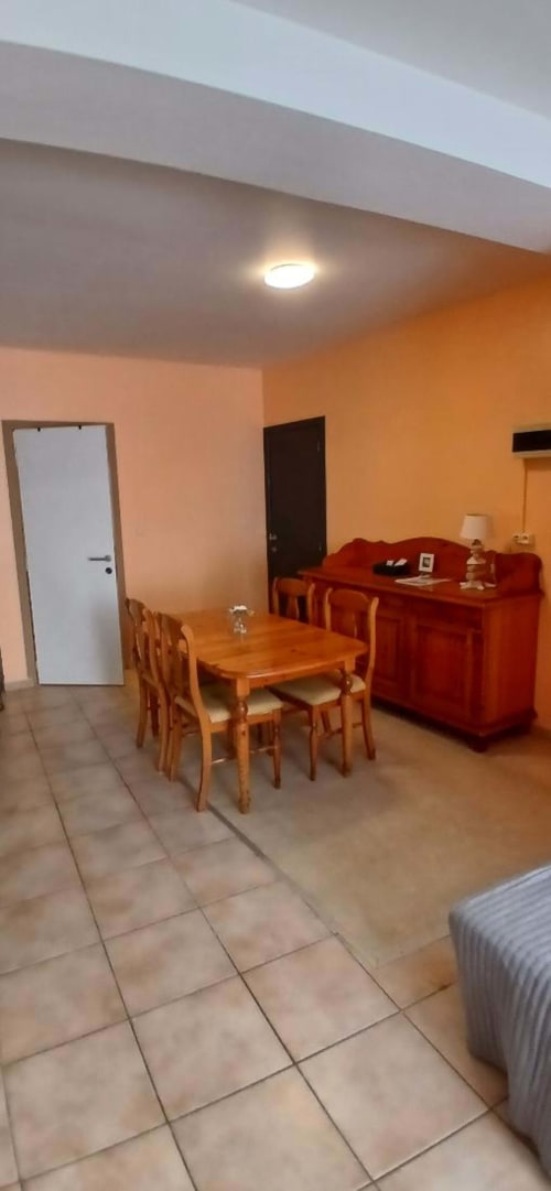 Apartment living room at Les Petits Nids De Nina in Fosses-la-Ville with wooden dining table, red furniture, and orange walls