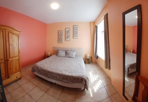 Bright bedroom at Les Petits Nids De Nina with orange walls, double bed, wooden wardrobe, and floor-to-ceiling mirror in