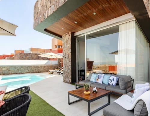 Modern villa terrace with turquoise pool, gray lounge seating, wooden furniture, and mountain views at Home Stay Gran Canaria