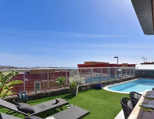 Luxury villa with private pool, green garden, modern lounge areas, and mountain views in Gran Canaria
