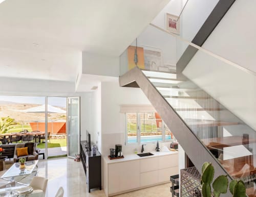 Modern villa interior in Gran Canaria with open kitchen, stairs, and pool view through glass doors