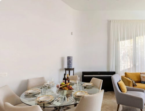 Modern villa dining room with round glass table, piano, and yellow seating at Home Stay Gran Canaria