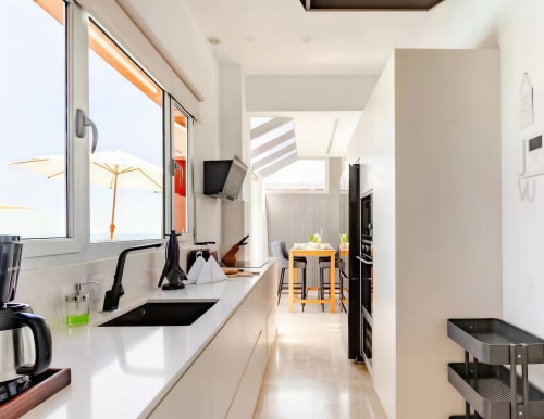 Modern kitchen in Sweet Green 21 villa at Home Stay Gran Canaria with white cabinetry, black sink, and dining area visible