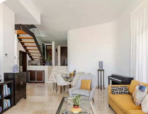 Modern villa living room with yellow sofa, white armchair, wooden staircase, and pool view at Home Stay Gran Canaria
