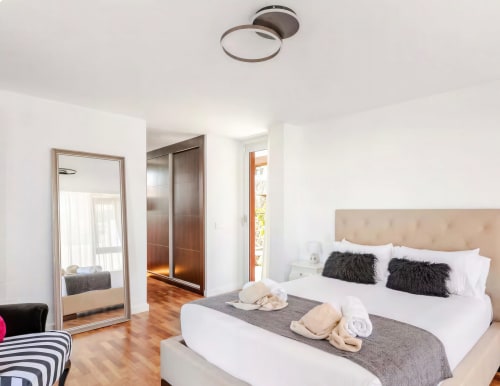 Bright modern bedroom at Home Stay Gran Canaria villa with king bed, black cushions, wood flooring, and pool view balcony