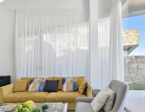 Modern living room with mustard yellow sofa, white sheer curtains, and stone accent wall at Home Stay Gran Canaria villa