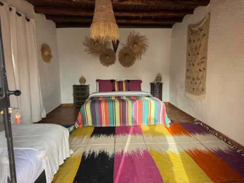 Lit à rayures colorées dans la suite rooftop de l'hôtel Eucalyptus Ethnic avec décoration tissée et mobilier marocain traditionnel