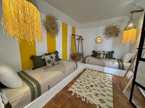 Suite lumineuse sur le toit de l'hôtel Eucalyptus Ethnic avec accents jaunes, luminaires en macramé, lits jumeaux et décor marocain